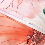 Pościel satyna bawełniana 180x200 Camellia w kolorze kremowym z pomarańczowymi kwiatami. Widoczny zamek błyskawiczny i delikatna faktura materiału. Ułożona w sposób leżący, ukazująca detale wzoru oraz wykończenie.