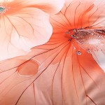 Kremowa pościel satynowa 220x200 cm z nadrukiem pomarańczowych kwiatów. Zbliżenie na szczegóły kwiatu, ukazujące delikatne płatki i wodne krople. Materiał gładki, błyszczący, idealny do eleganckich wnętrz.