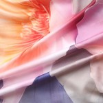 Pościel satyna bawełniana 140x200 Aurora w białym i niebieskim kolorze z pastelowymi różowymi kwiatami. Materiał gładki, z subtelnym połyskiem, ukazany w zbliżeniu, z widocznymi detalami wzoru kwiatowego.