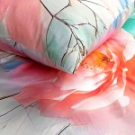 Pościel satyna bawełniana 180x200 Roselle w odcieniach szaro-zielonych z dużymi różowymi kwiatami. Zestaw zawiera poszewki oraz prześcieradło, układany na łóżku, z bliskim ujęciem detali wzoru i faktury materiału.