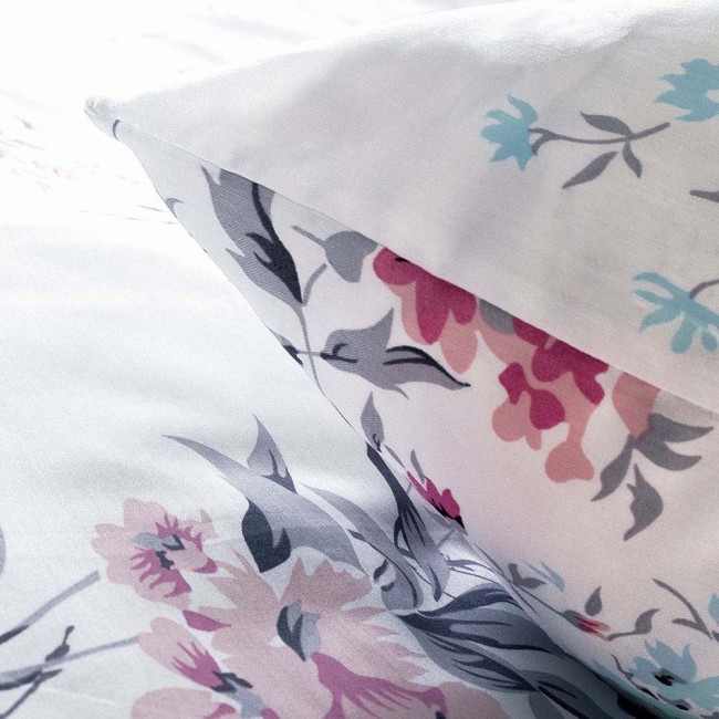 Pościel satyna bawełniana 200x220 cm w białym kolorze z wiosennym wzorem różowych i niebieskich kwiatów. Kąt ujęcia zbliżony na poduszkę i część poszwy, ukazujący detale kwiatowe oraz subtelną fakturę materiału.