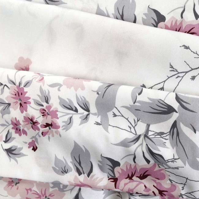 Pościel satyna bawełniana 200x220 cm w białym kolorze, ozdobiona wiosennymi różowymi i niebieskimi kwiatami. Widoczny wzór kwiatowy na gładkiej powierzchni, z delikatnymi liśćmi w odcieniach szarości.