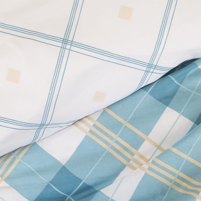 Pościel bawełniana 160x200 w kolorze białym i błękitnym, z wzorem kraty. Widoczne linie w odcieniu błękitu i kremu. Produkt leży na płasko, ukazując detale materiału oraz wyrazisty wzór. Tło jest jasne, co podkreśla kolory pościeli.