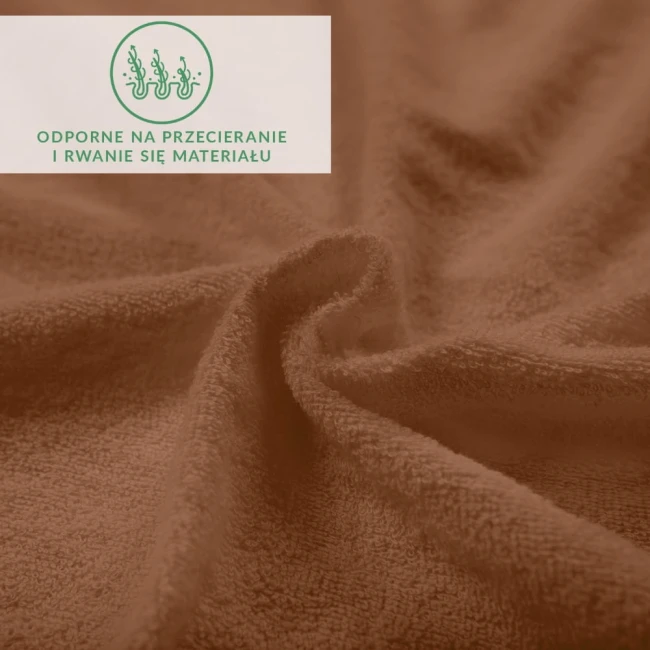 Prześcieradło frotte z gumką w kolorze czekolady, wykonane z miękkiego materiału, leżące na płaskiej powierzchni. Widoczna struktura tkaniny oraz delikatne zakładki. Tło w odcieniach brązu, akcentuje kolor prześcieradła.