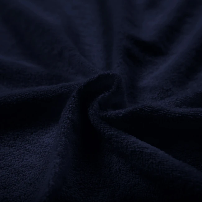 Pościel frotte 155x220 w ciemnym niebieskim kolorze, granatowym, o miękkiej, teksturowanej powierzchni. Zbliżenie na materiał ukazujące jego fakturę i delikatne marszczenia.