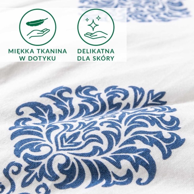 Pościel bawełniana 135x200 z niebieskim ornamentem na białym tle, eksponująca delikatny wzór roślinny. Zbliżenie na fakturę dzianiny jersey, podkreślające miękkość materiału, odpowiednie dla skóry. Grafika z symbolami wskazującymi na cechy tkaniny.