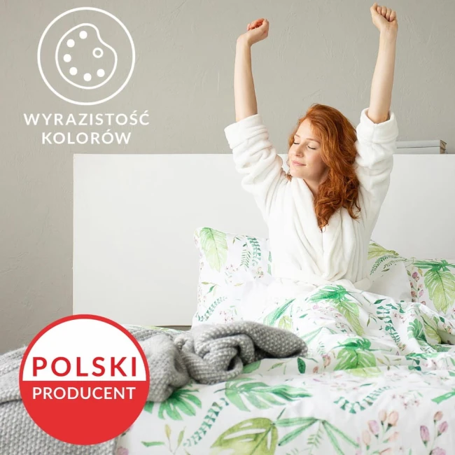 Pościel bawełniana 135x200 w kolorze białym z zielonymi wzorami roślinnymi. Komplet składa się z poduszki i narzuty. Produkt leży na łóżku, w tle widoczna gładka ściana. Na narzucie znajduje się szary, teksturowany koc.