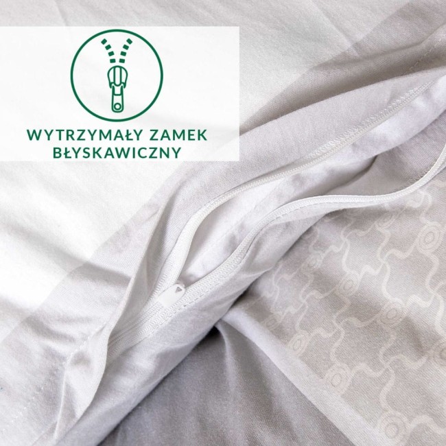Zbliżenie na zamek błyskawiczny w pościeli bawełnianej 135x200 . Widoczne białe tkaniny z dekoracyjnym ornamentem oraz wytrzymały zamek. Pościel rozłożona, ukazująca teksturę dzianiny jersey. Tło jasne, minimalistyczne.