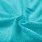 Poszewka frotte 80x80 w kolorze turkusowym, z miękką, teksturowaną powierzchnią. Widok zbliżony, ukazujący plisowanie materiału i jego intensywny kolor.