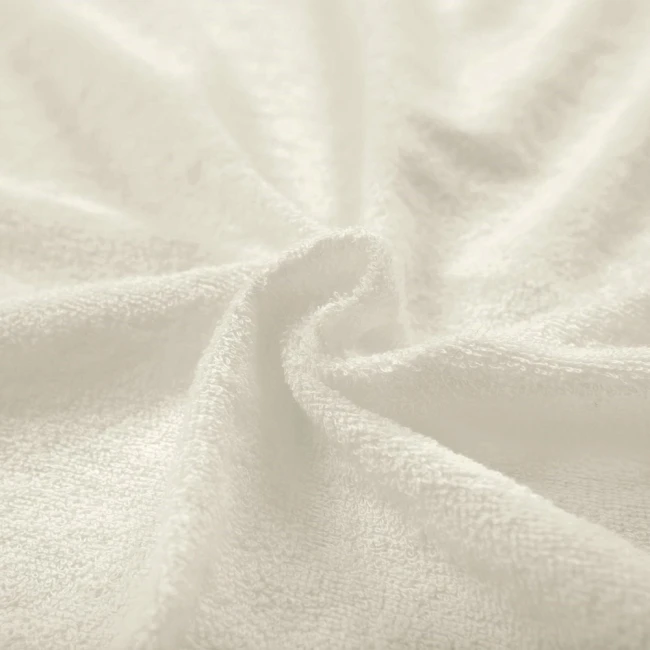 Poszewka frotte 40x80 w kolorze ecru, o miękkiej, teksturowanej powierzchni. Złożona w falę, ukazuje delikatne włókna materiału. Idealna do wykorzystania na poduszki, zapewniająca komfort i estetyczny wygląd.