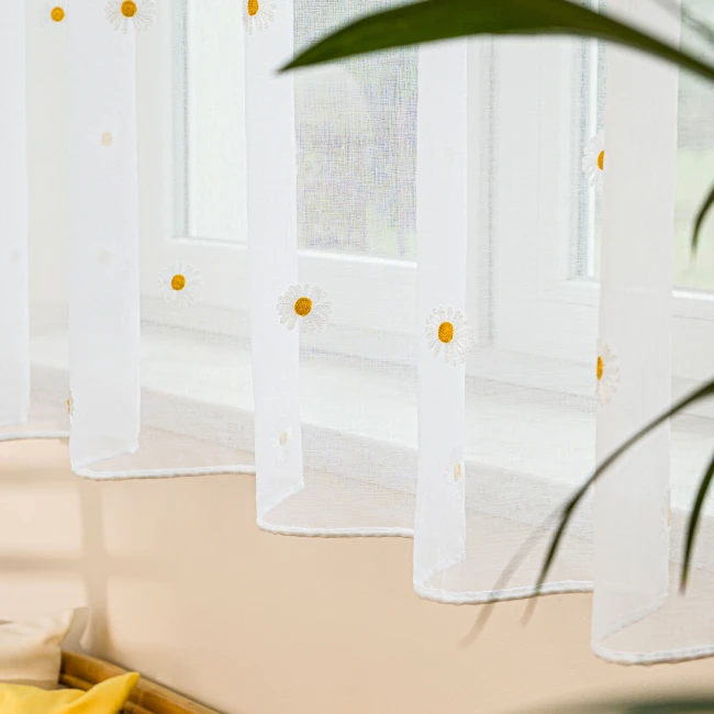 Firana BELLIS z etaminu, haftowana w stokrotki, biała, z ołowianką. Zawieszona w oknie, prezentuje delikatny wzór z żółtymi środkami kwiatów, z krawędzią wykończoną na gładko. Wymiary 300 x 160 cm.