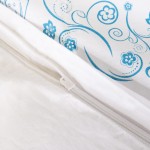 Pościel bawełniana 220x200 Cottonlove w kolorze białym z niebieskim wzorem kwiatowym. Widoczny zamek błyskawiczny. Ujęcie z góry, ukazujące detale materiału oraz fakturę. Produkt rozłożony, na jednolitym tle.