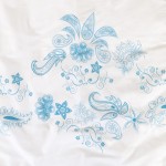 Pościel bawełniana 220x200 Cottonlove 71464/1 w kolorze białym z niebieskim wzorem w kwiaty i paisley. Produkt leży na płaskiej powierzchni, z widocznym detalem dekoracyjnym. Wzór jest dużych rozmiarów, wyraźnie zaznaczony na tkaninie.