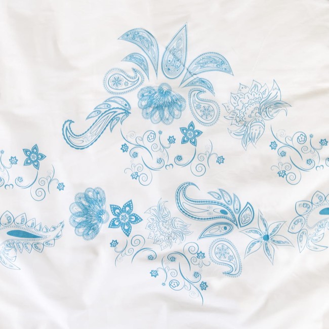 Pościel bawełniana 220x200 Cottonlove 71464/1 w kolorze białym z niebieskim wzorem w kwiaty i paisley. Produkt leży na płaskiej powierzchni, z widocznym detalem dekoracyjnym. Wzór jest dużych rozmiarów, wyraźnie zaznaczony na tkaninie.