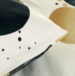 Pościel satyna bawełniana 220x200 Linure w kolorze białym z geometrycznym wzorem w beżu oraz czerni. Widoczna poduszka z detalami czarnych kółek i kropek na tle białym, ułożona na płaskiej powierzchni. Wzór nowoczesny i minimalistyczny.