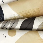 Pościel satyna bawełniana 220x200 w kolorze białym z geometrycznym wzorem w odcieniach beżu i czerni. Widoczne różne kształty i linie, tworzące nowoczesny, abstrakcyjny design. Ułożona w złożony sposób, ukazująca teksturę materiału.