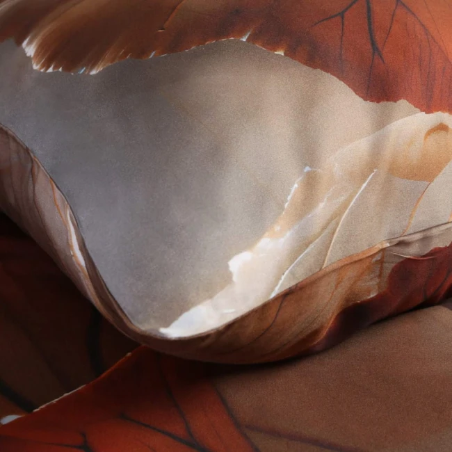 Pościel satyna bawełniana 200x200, kolor beżowy z wzorem liści, z bliska. Złożona na łóżku, ukazująca gładką teksturę materiału, subtelne detale. Widoczny jeden kąt poduszki oraz fragment narzuty, bez napisów i logo.