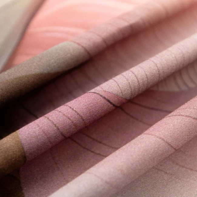 Pościel satyna bawełniana 220x240 w odcieniach różu i szarości, z nadrukiem kwiatów. Złożona, ukazująca gładką fakturę tkaniny. W tle jasne, neutralne, co eksponuje wzory i kolory materiału.