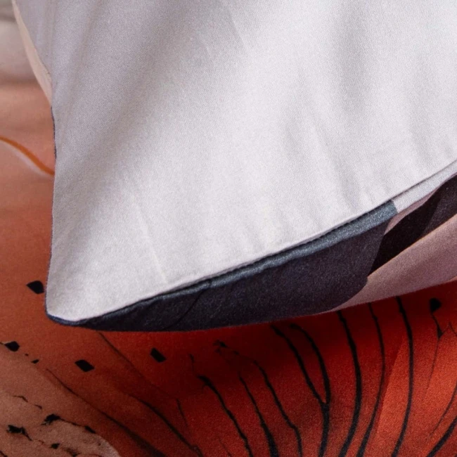 Poszewka z satyny bawełnianej w kolorze szarym, rozłożona na łóżku, z widocznymi pomarańczowymi kwiatami. Kąt ujęcia z boku ukazuje detale wykończenia oraz drobną teksturę materiału. Produkt o wymiarach 200x200 cm, idealny do zestawów pościeli.