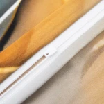 Zbliżenie na zamek błyskawiczny pościeli satynowej 220x200 cm w kolorze złotym i turkusowym. Widać gładką fakturę materiału oraz różnorodne odcienie w tle. Zamek jest biały, dobrze widoczny na tle tkaniny.