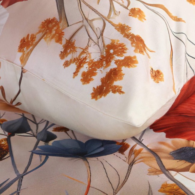 Pościel satyna bawełniana w kolorze kremowym z wzorem polnych czerwonych kwiatów. Złożona kołdra i poduszka pokazują delikatne hafty oraz żywe kolory kwiatów, z niebieskimi akcentami. Kąt ujęcia z boku, na jednolitym tle.