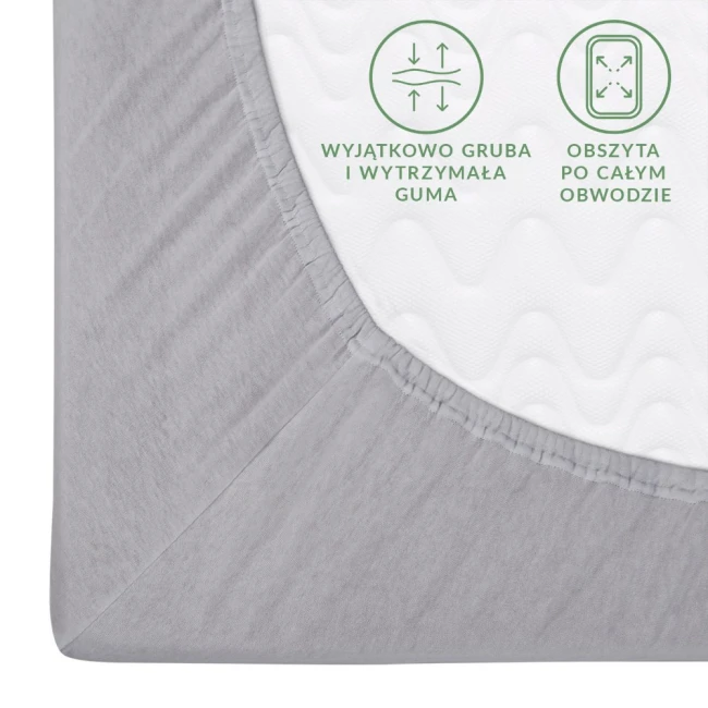 Prześcieradło jersey z gumką w kolorze popielatym, rozmiar 60x120 cm. Widoczne obszycie po całym obwodzie oraz wyjątkowo gruba, elastyczna guma. Kąt ujęcia z góry, produkt leży na płaskiej powierzchni. Tło neutralne, skupia uwagę na detalu materiału.