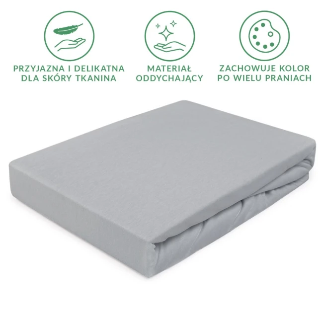 Prześcieradło jersey z gumką w kolorze popielatym, rozmiar 70x140 cm, leżące na gładkim tle. Wykonane z delikatnego, oddychającego materiału, z widocznymi fałdami tkaniny. Brak napisów lub logo na powierzchni.