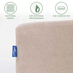 Prześcieradło jersey z gumką 70x140 w kolorze beżowym, leżące na białym tle. Widoczna tekstura materiału oraz niebieska metka. Grafiki informacyjne: materiał jersey, nie wymaga prasowania, nie gniecie się.