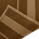 Ręcznik bambusowy 70x140 w jasnym brązie, składany, z widocznymi poziomymi paskami o jaśniejszym odcieniu. Materiał o miękkiej, teksturowanej powierzchni. Ujęcie z góry, zbliżenie na krawędź i detale wykończenia.