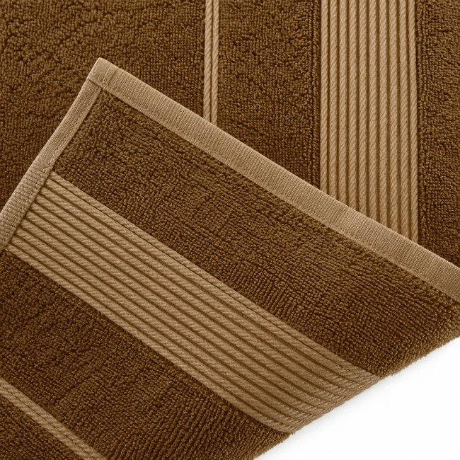 Ręcznik bambusowy 70x140 w jasnym brązie, składany, z widocznymi poziomymi paskami o jaśniejszym odcieniu. Materiał o miękkiej, teksturowanej powierzchni. Ujęcie z góry, zbliżenie na krawędź i detale wykończenia.