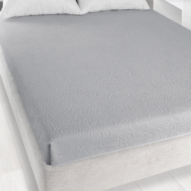 Prześcieradło żakardowe bez gumki w kolorze popielatym, o wymiarach 175x220 cm, rozłożone na łóżku. Posiada delikatny wzór w fakturze. W tle widoczna jest część jasnego materaca i białe poduszki.