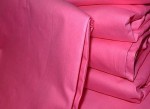 Poszewka wsypowa 50x60 w kolorze różowym, wykonana z gładkiego materiału. Produkt leżący, złożony w kilka warstw, prezentujący intensywny, jednolity kolor. Brak widocznych napisów lub logo. Tło jednostajne.